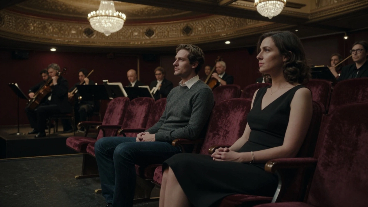 A couple and woman in elegant attire watching a performance under theater chandeliers.