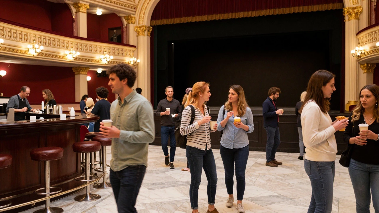 Crowd of people socializing and having drinks in a bright theater lobby during intermission